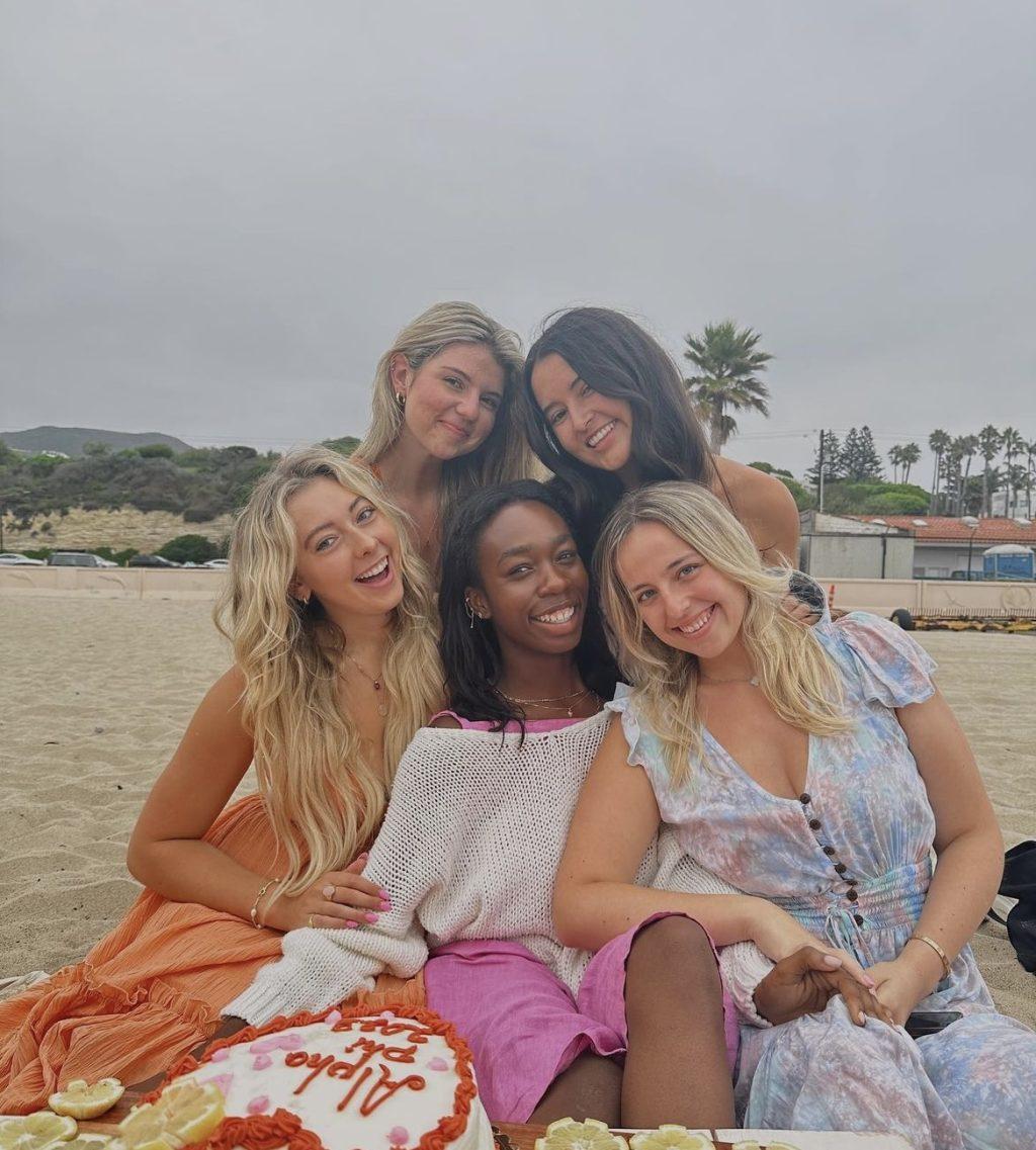 Friends pose with Deslyn and Peyton at a beach picnic.