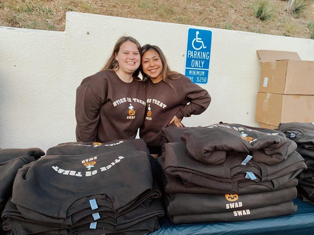 Sydney Wilson and Sandy Galeas hand out Halloween-themed Charlie Brown crewnecks at Stick-or-Treat on Oct. 26, at the Student Health Center. The first 100 students to get their free flu shot received a crewneck designed by the Student Wellness Advisory Board. Photos by Rachel Flynn
