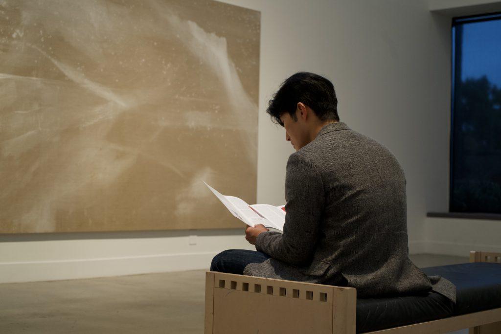 An attendee reads Fujimura&squot;s "Art + Faith" in the Weisman Museum on Jan. 20. The museum sold the book at the gallery entrance.