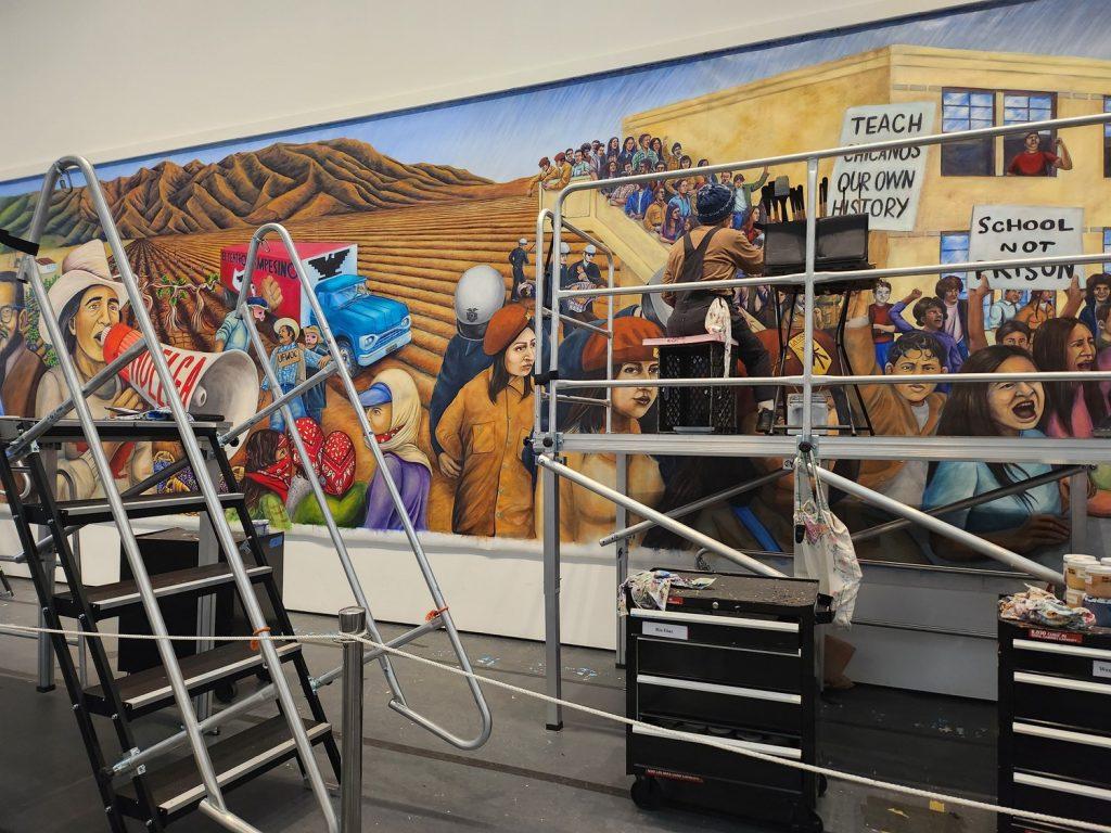Artist Rio Diaz paints a section depicting the Chicano Movement for “The Great Wall of Los Angeles” on March 29, in LACMA. The section is part of the expansion of the wall into the 21st century, according to LACMA. Photos by Madison Luc