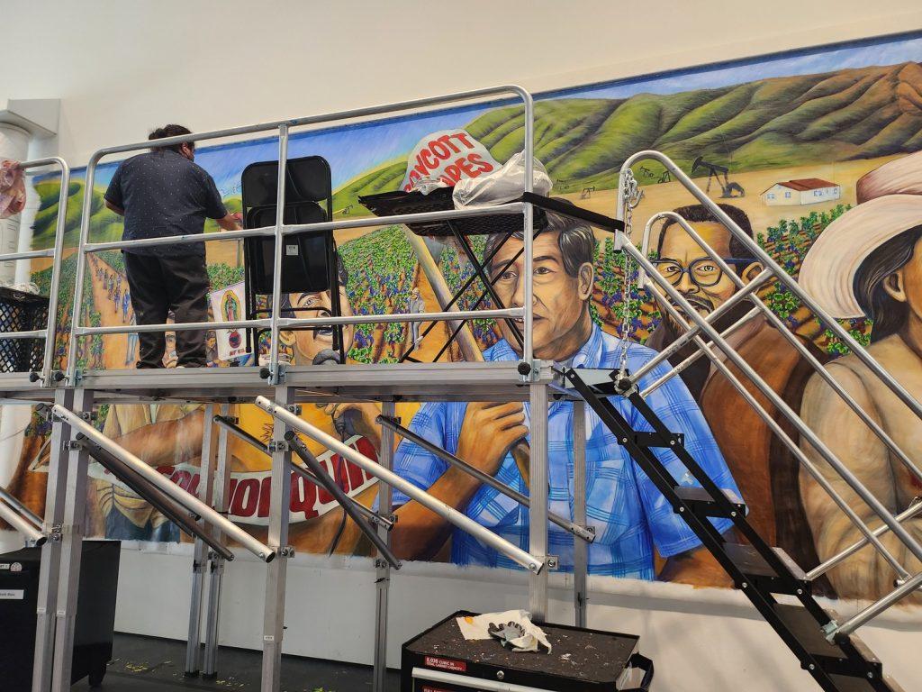 Artist Wenceslao Quiroz paints a scene commemorating the Delano grape strike March 29, in LACMA. Mendoza said they use lightfast, Golden brand paint on a Polytab canvas then coat the piece with a SPARC-designed coating for UV and vandal protection called MuralShield to withstand the elements.