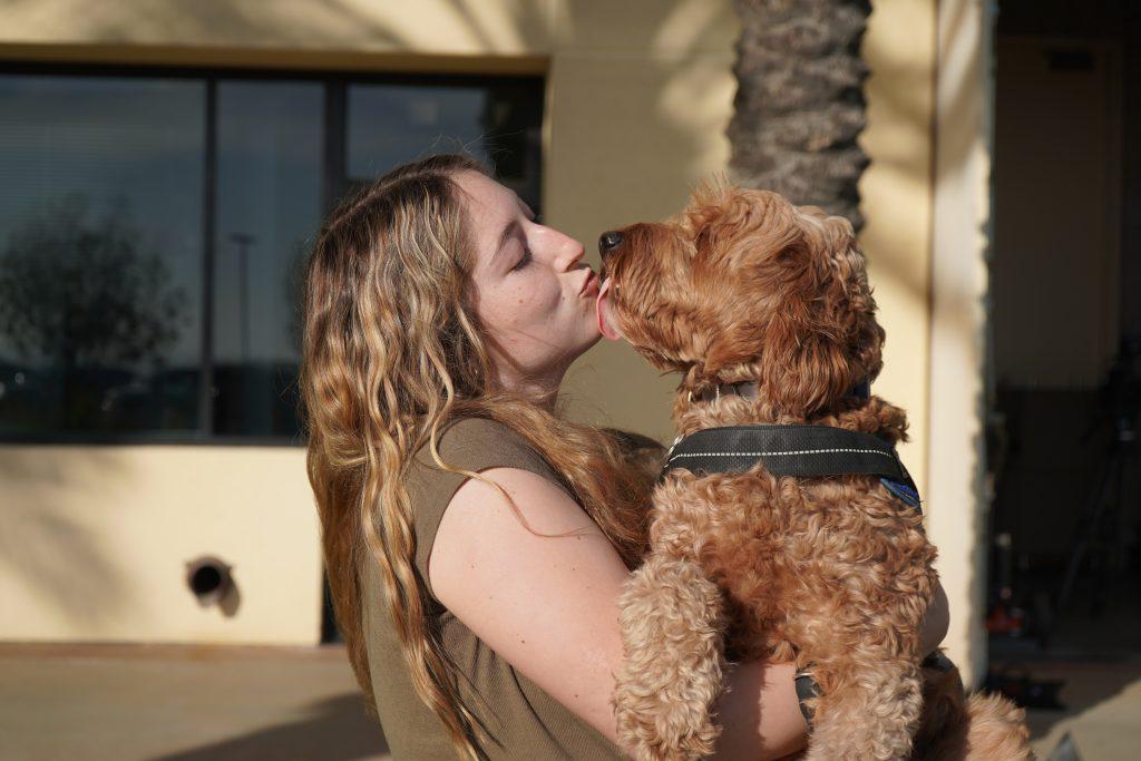 Junior Caroline Speed leans in to kiss her psychiatric support dog, Ollie, in front of the Center for Communication and Business on March 25. Caroline has cared for Ollie since he was just an 8-week-old puppy. Photo by Liam Zieg