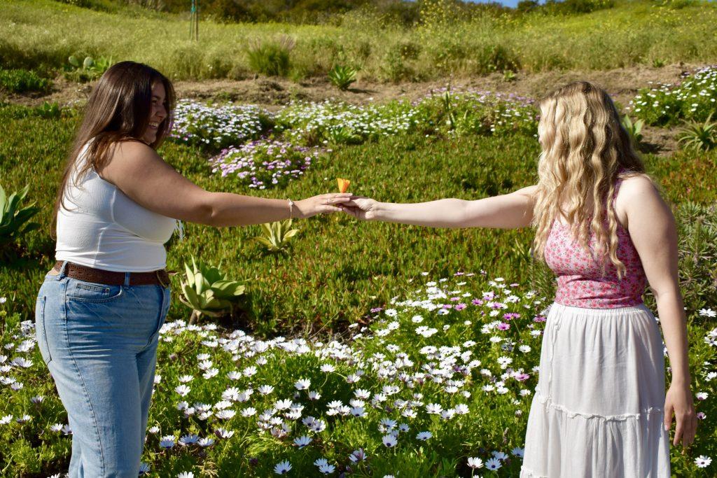Senior Lainey Fenn and Junior Kyra Hatton reach toward one another in a flower field on Malibu Road on March 22. Thema Bryant-Davis, a psychology professor at the Graduate School of Education and Psychology, said hope is the capacity one has to move forward despite being in difficult circumstances. Photo by Mary Elisabeth