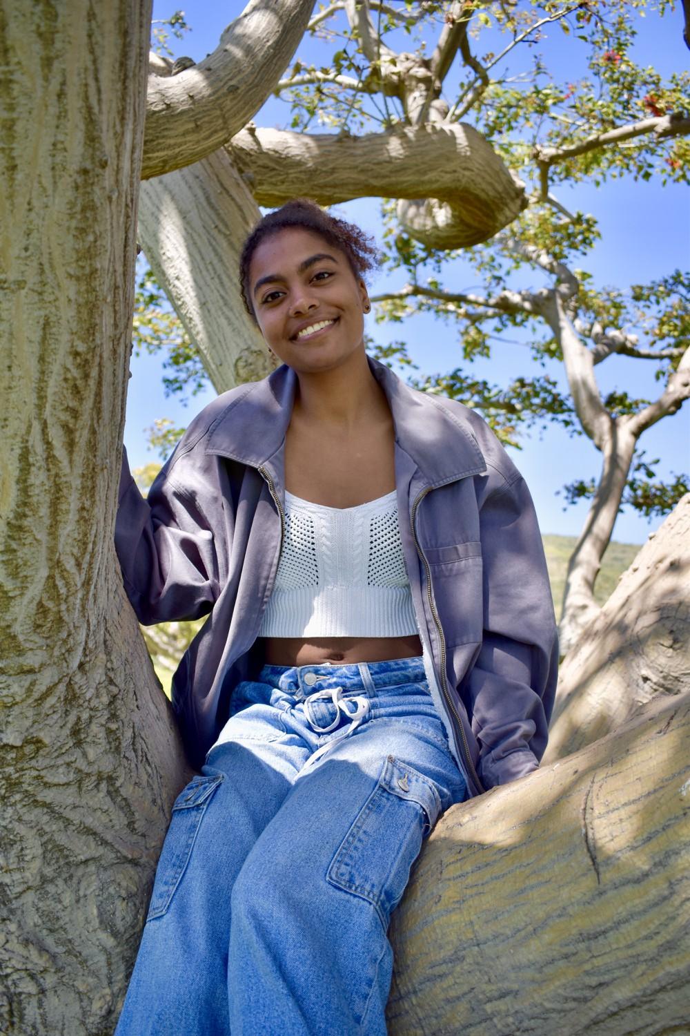 Junior Alia Grogan sits in a tree on Alumni Park. Grogan said she goes to Alumni to connect with God.
