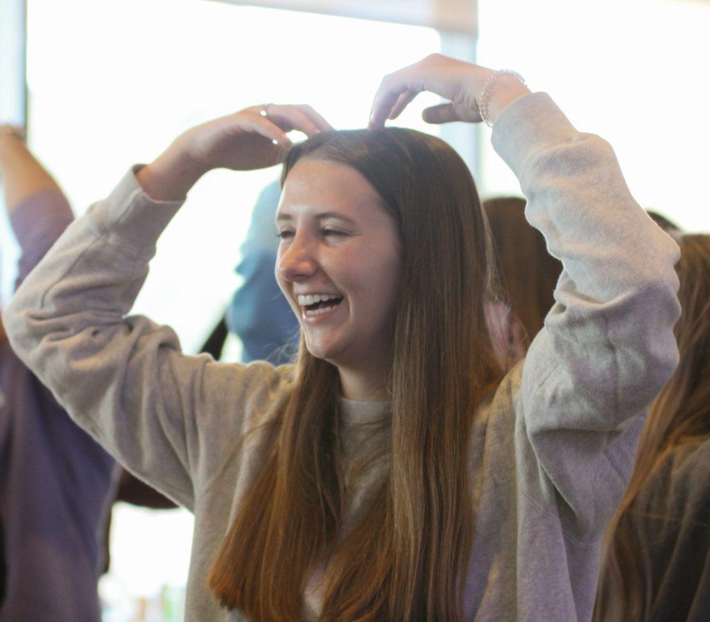 Sophomore Carly Duerre smiles as she dances the "Y.M.C.A." at Creative Cafe on March 23, in the Fireside Room. The group of 80+ people spent time together engaged in creative relief activities like dancing and coloring rocks.