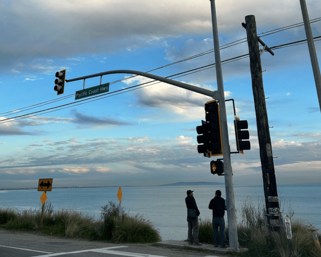 Pedestrians stand on the side of PCH at the entrance of Topanga Canyon in February. Drivers need to be vigilant of both other vehicles and pedestrians while on the highway, Malibu residents said. Photo by Yamillah Hurtado
