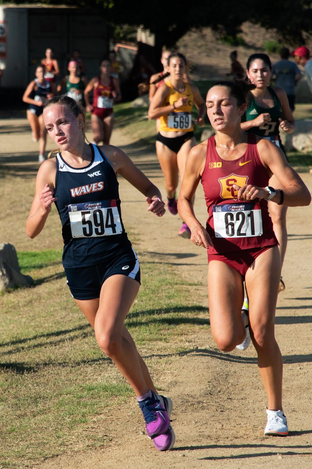 Sophomore runner Lizzy Crawford strides just ahead of a USC runner during the Waves Invitational on Aug 30, at Alumni Park. During her true freshman season, Crawford was the top runner in all five races she competed in, following her freshman year with a top finish in her first race as a sophomore.