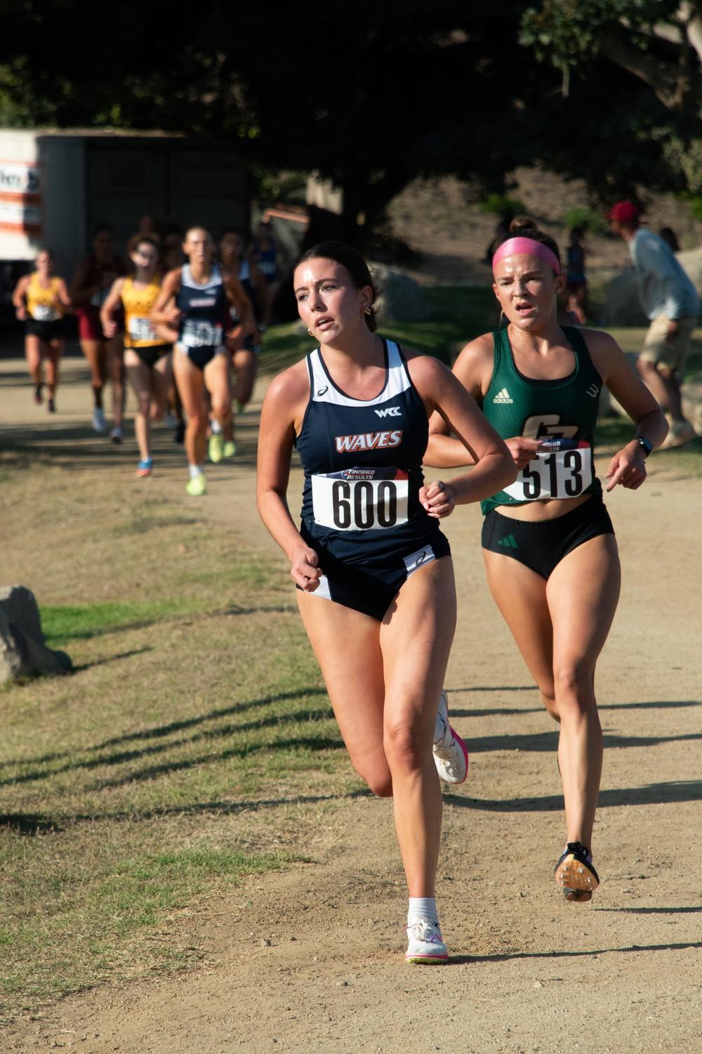 Senior runner Eden Mittelsdorf races ahead of a Cal Poly SLO runner Aug 30, at Alumni Park. Mittelsdorf secured the second highest finish for the Waves at 13th with an end time of 13:43:00.