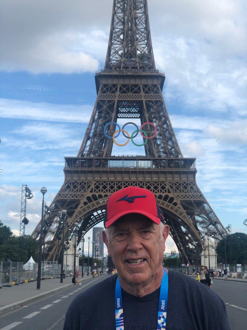 Dunphy smiles as he poses in front of the Eiffel Tower as it holds the iconic Olympic Rings at the 2024 Paris Olympics. Dunphy has helped both Men's and Women's Volleyball teams to six Olympic medals. Photo courtesy of Marv Dunphy