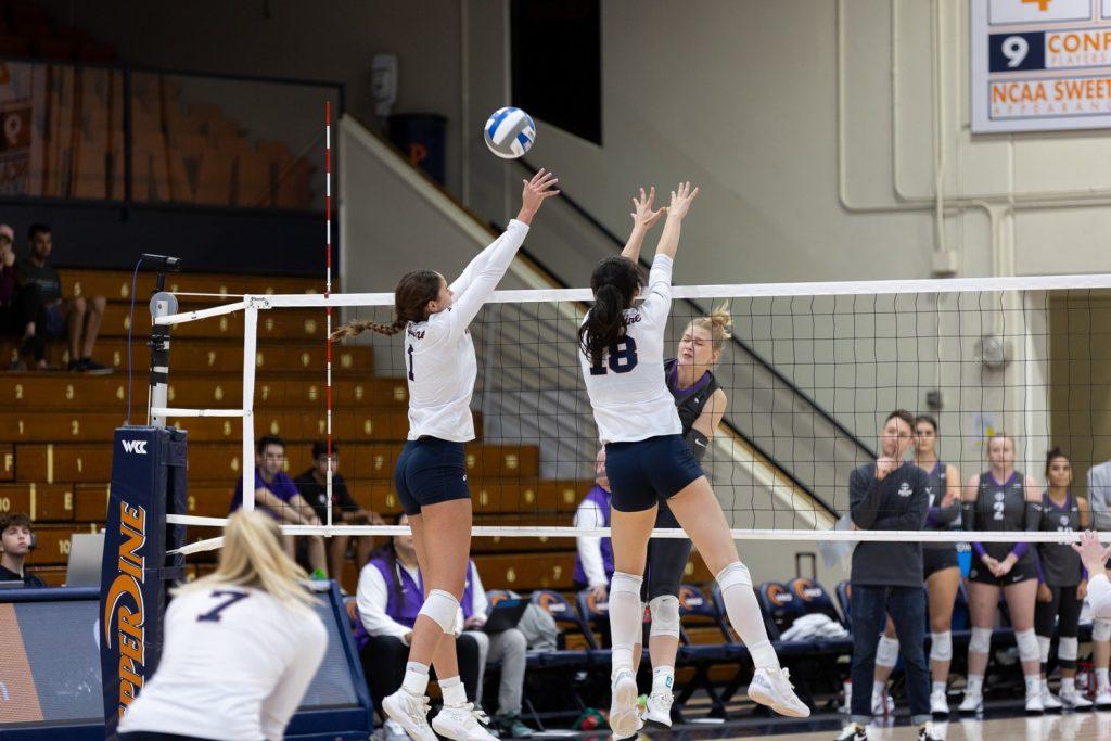 Freshman middle blocker Ella Piskorz and senior outside hitter Grace Chillingworth attempt a block on the Portland attack Oct. 19 at Firestone Fieldhouse. Piskorz led the match in blocks with six, along with four kills.