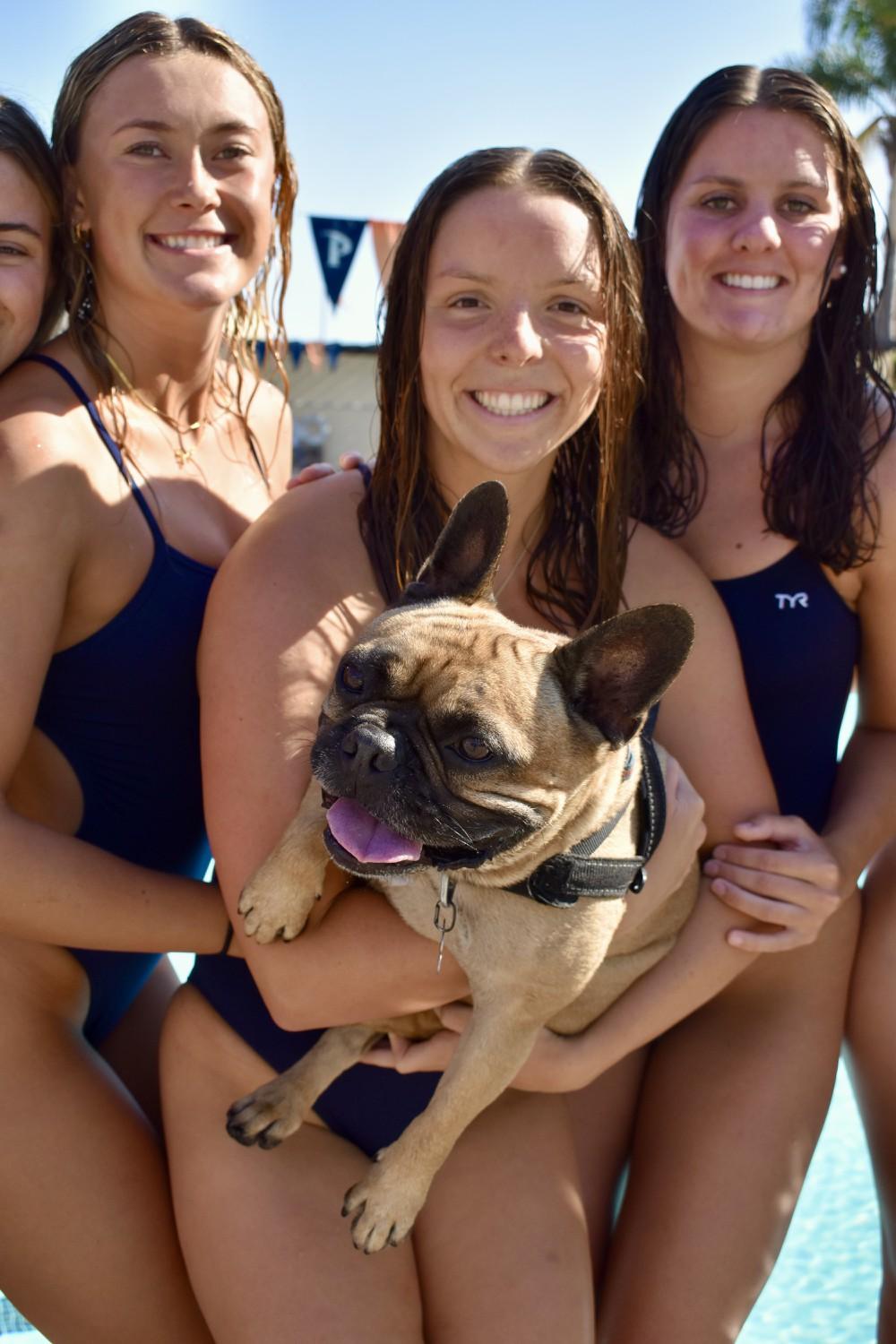 AJ Adams, Anna Ryan and Lindsay Hemming pose with Tank, Head Coach Ellie Monobe's dog, Oct. 2. Tank attends swim meets at Pepperdine.