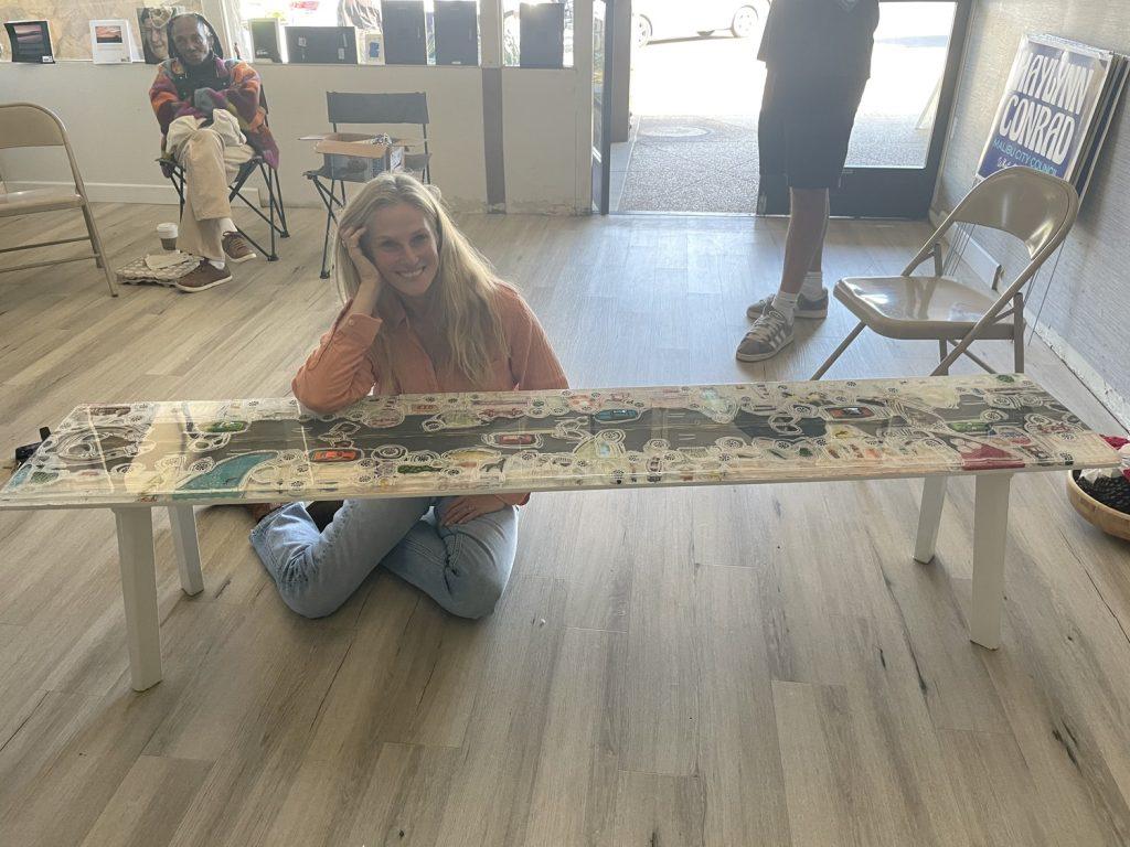 Haylynn Conrad poses with a bench she made for her City Council campaign. The bench is a model of PCH with 61 ghost tires and Emily Shane's bracelet encased in the resin mold.