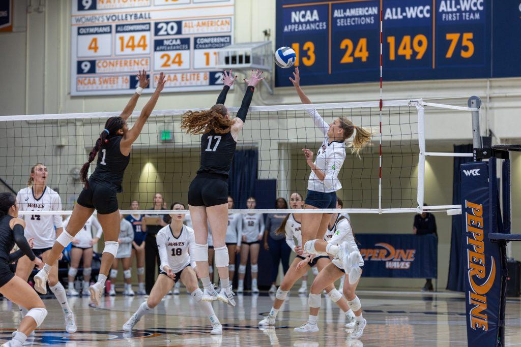 Senior outside hitter Birdie Hendrickson tips the ball over two LMU blockers at Firestone Fieldhouse on Nov. 7. Hendrickson ended the match with 16 kills and led multiple comebacks for the Waves against the Lions.