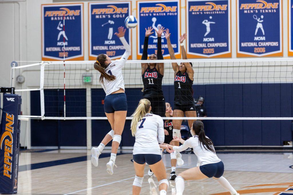 Senior outside hitter Grace Chillingworth goes for a kill against two LMU blockers at Firestone Fieldhouse on Nov. 7. Chillingworth ended the match with 19 kills but the Waves were unable to beat the Lions. Photos by Colton Rubsamen