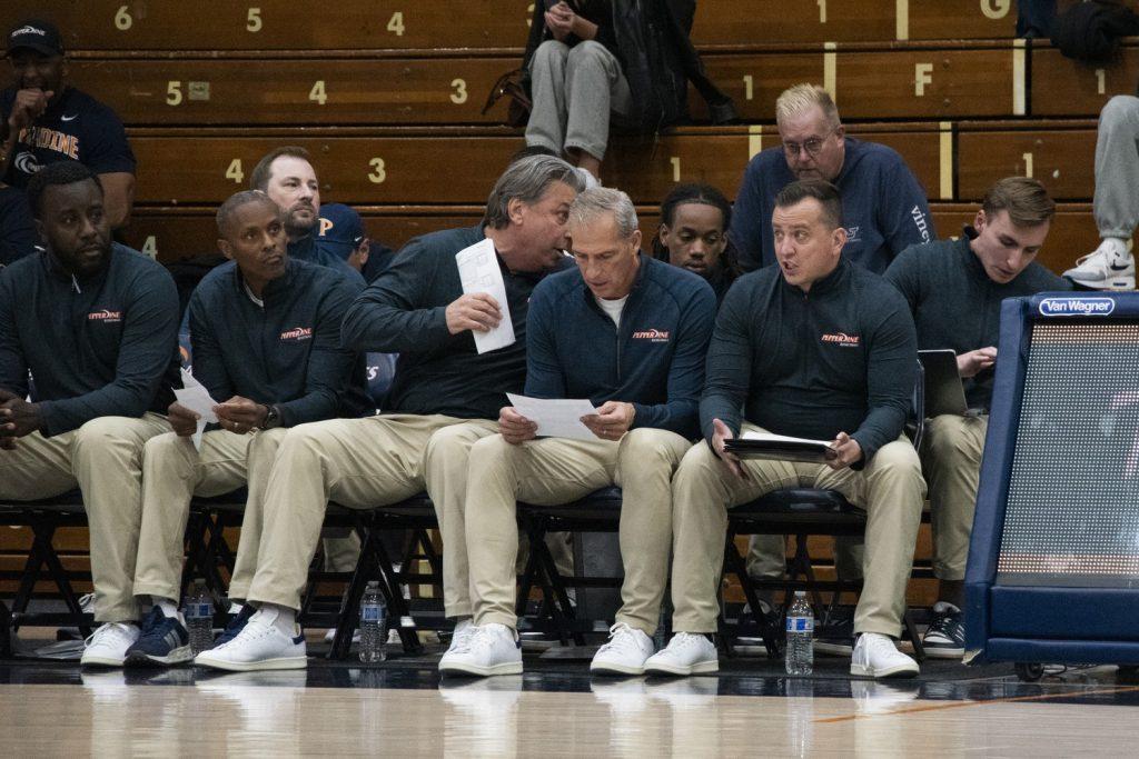 Ed Schilling (second to the right) with his coaching staff as his team awaits the start of their home opener against Western Illinois University on Nov. 6 at Firestone Fieldhouse. This was the first game of the Men's Basketball season, resulting in their first win of the season with a score of 77-64. Photo by Perse Klopp