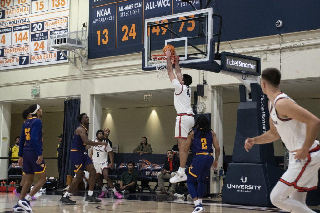 Graduate student forward Alonzo Faure dunks the ball against Western Illinois on Nov. 6 at Firestone Fieldhouse. Faure secured four points and three boards in his debut match for the Waves.