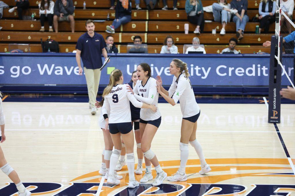 The Waves celebrate after senior outside hitter Grace Chillingworth wins the set with a kill Nov. 30 at Firestone Fieldhouse. Chillingworth ended the match with 17 kills and three assists for her final game with the Waves.