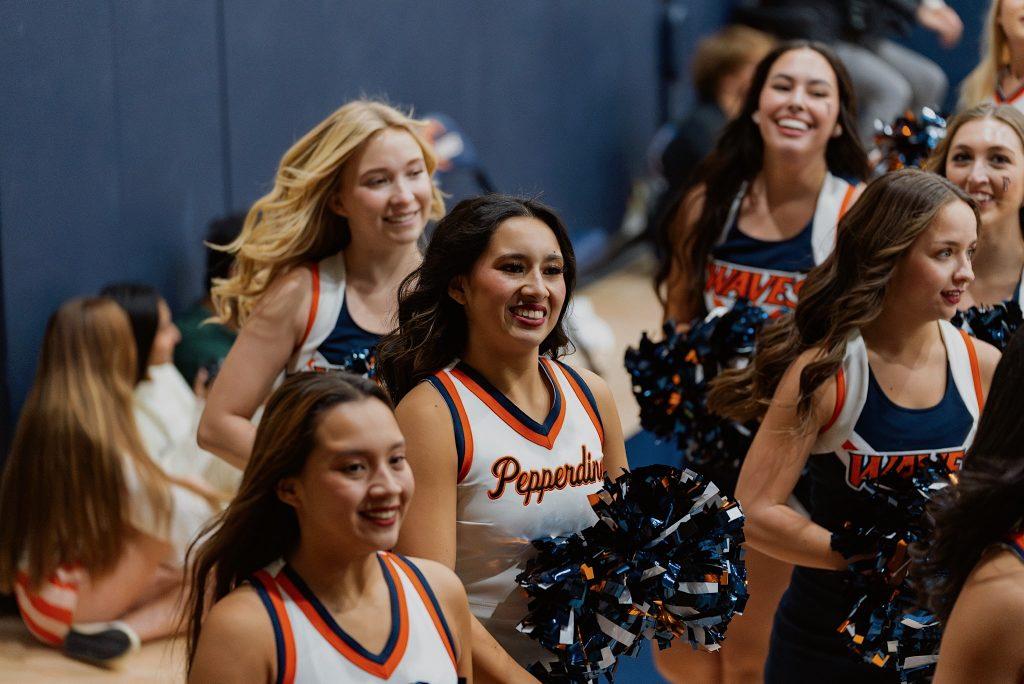 Pepperdine cheerleaders celebrate after a halftime performance in Firestone Fieldhouse on Nov. 6. The cheerleader in the middle of the photo is freshman Nevaeh Trelles, one of the eight freshmen on the team.