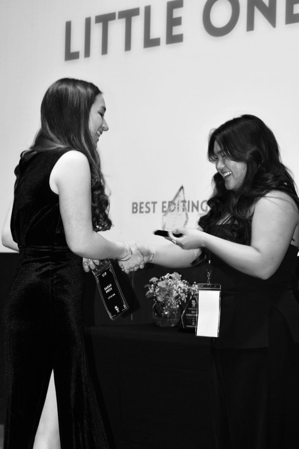 Sarah Breck (left) receives the Best Editing award from Caitlyn Garcia (right). The award marked her first-ever win at ReelStories Film Festival.