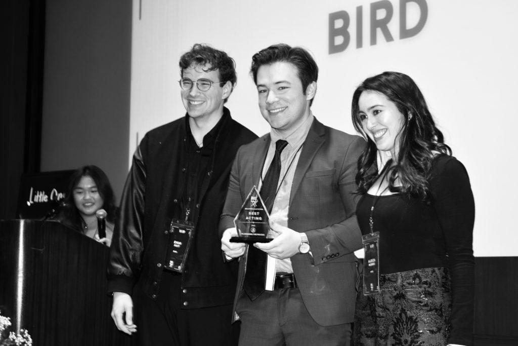 Nick Yi (middle), accompanied by Evan Huit (left) and Alekza Morris (right), accepts his award for Audience Choice in Elkins Auditorium on Jan. 31. In his film, Yi and Morris wore giant bird masks for a scene.