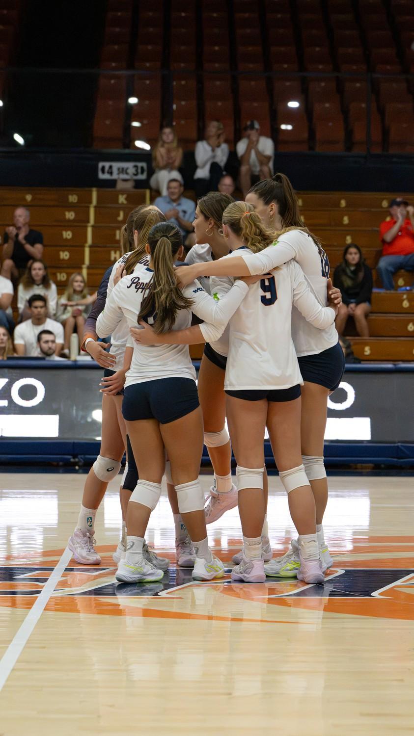 Pepperdine women’s volleyball players gather in a huddle to motivate one another during their match against Pacifica.